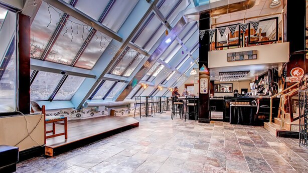 Eine moderne Bar mit hohen Decken und Oberlichtern, inklusive Bar und Sitzbereich.