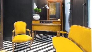 A room with a checkered floor, a yellow sofa, a wooden cabinet, and a mirror. - Design Apartment in Barrio Las Letras A02I (Madrid)