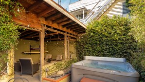 A hot tub with steps, surrounded by greenery and outdoor furniture. - Silver Surf Bungalow w/ Hot Tub - Steps from Beach (Oxnard)