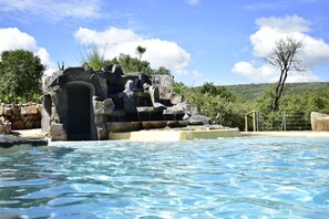 Una piscina de agua cristalina, rodeada de rocas y follaje.