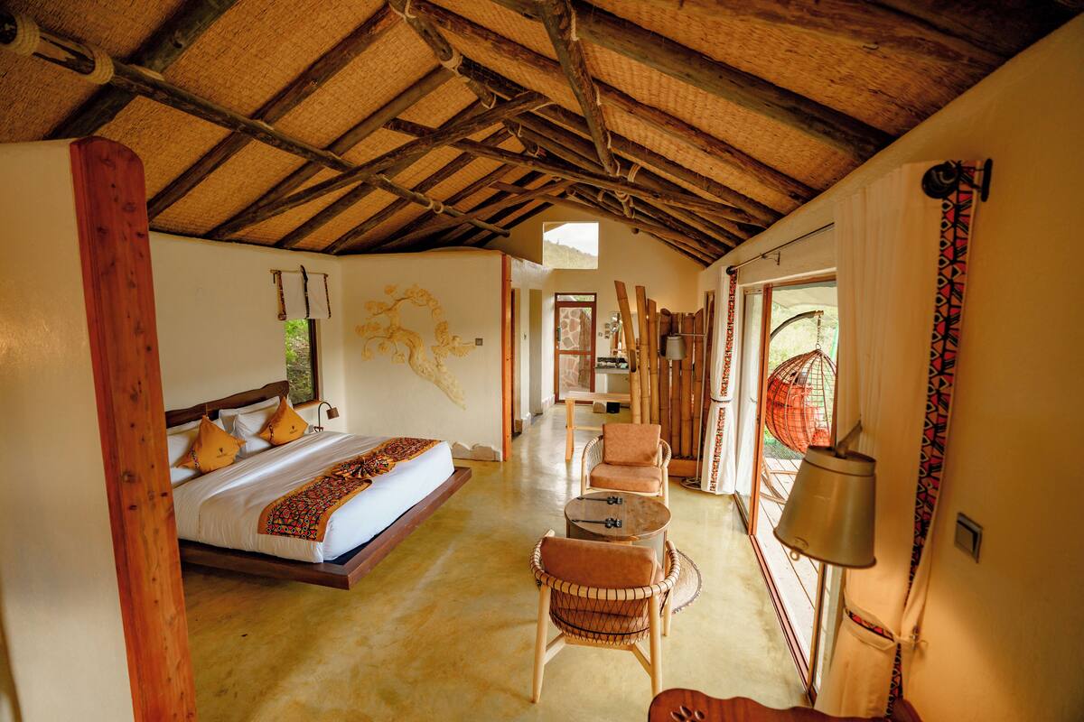 Um quarto com uma cama, duas cadeiras, uma mesa e um abajur.