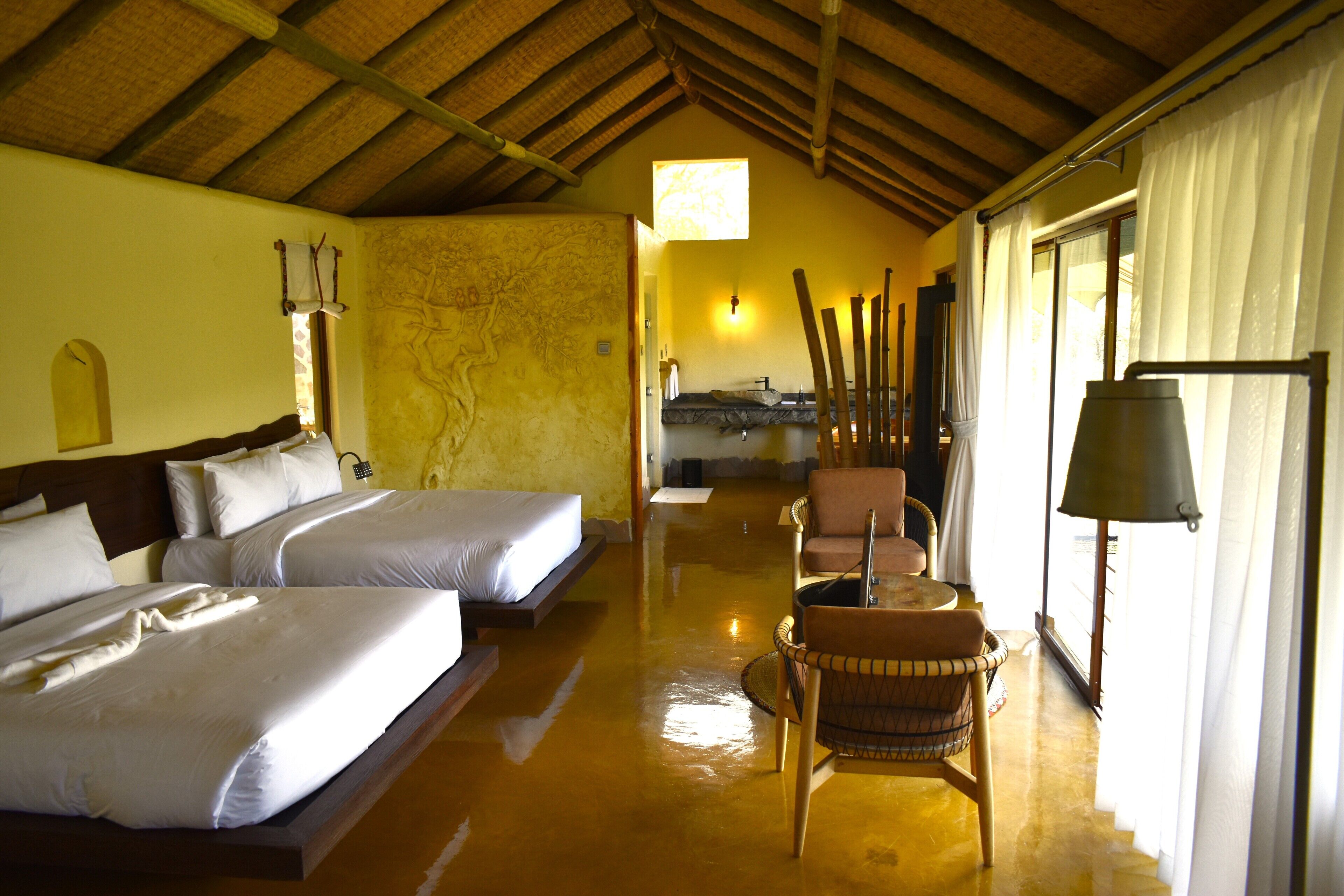 Une chambre d’hôtel avec deux lits, un plafond en bois, une carte accrochée au mur, une chaise et une lampe.