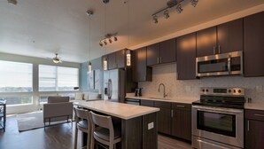 Una cocina moderna con armarios de madera oscura, electrodomésticos de acero inoxidable y una isla grande con taburetes de bar.