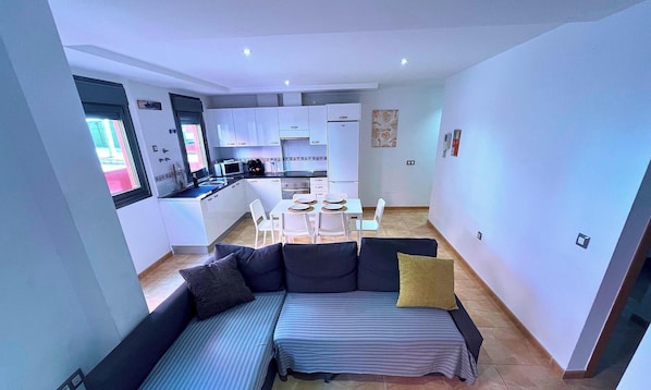 A compact living space with a kitchenette, a dining area, and a sofa with cushions. - Casa Roja | Puerto del Rosario | 2 Bedrooms, Patio e Terrace (Puerto del Rosario)