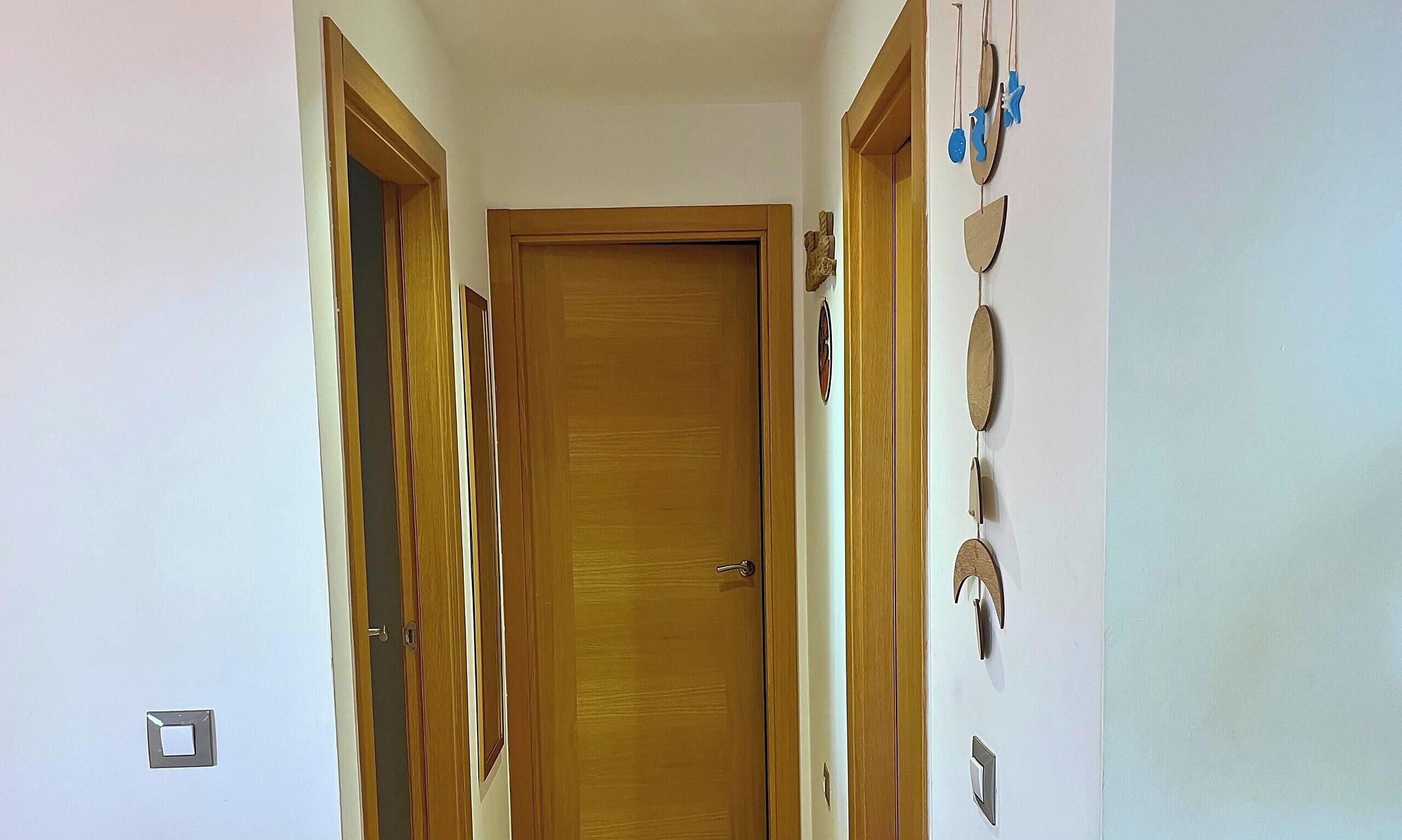 Ein Flur mit einer Holztür am Ende, einem Lichtschalter und Schlüsseln an der Wand.
