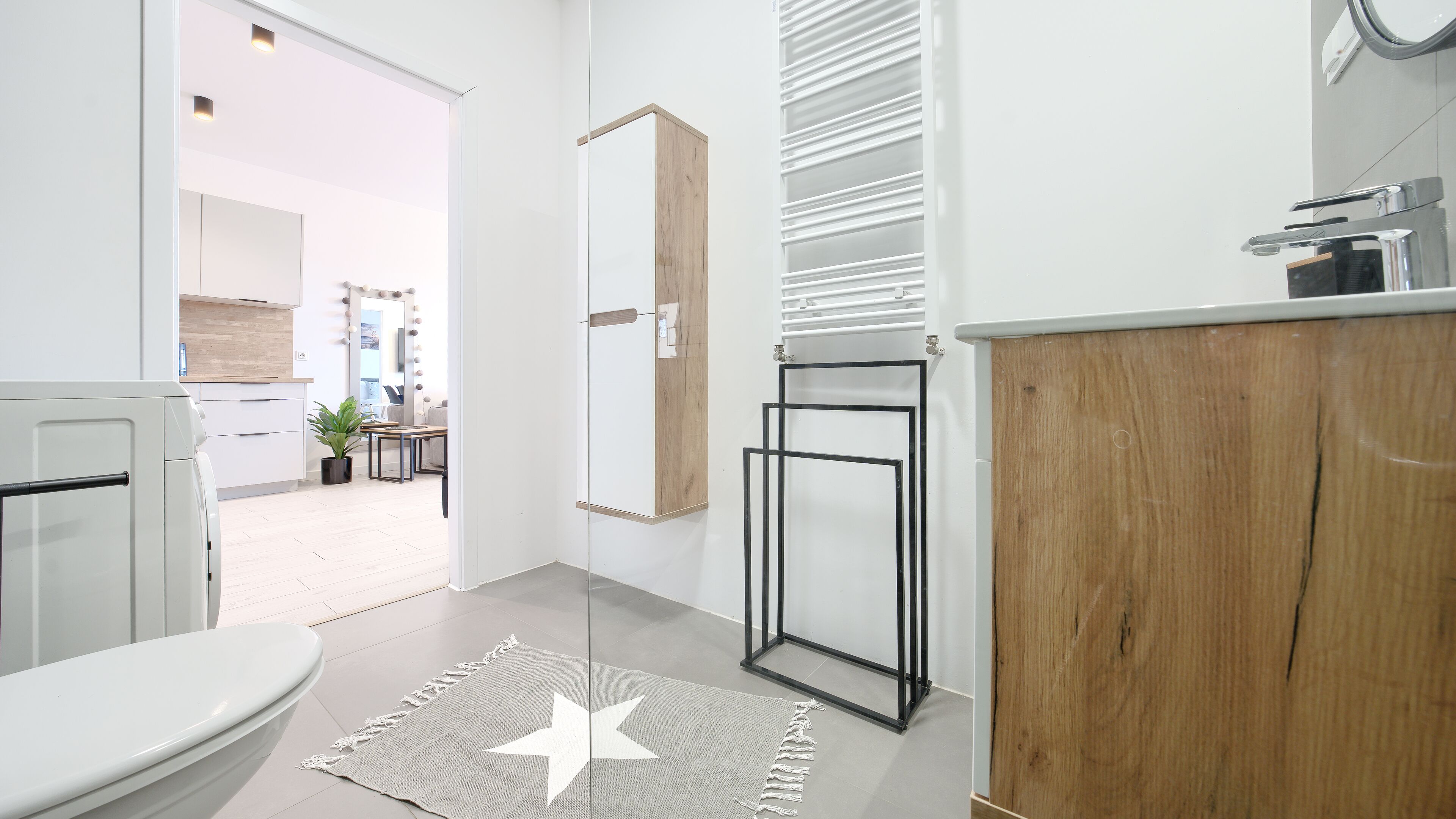 A modern bathroom with a wooden vanity, a mirror, and a toilet.