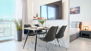 A modern hotel room with a dining area, a bed, and a TV mounted on the wall. - Apartamenty Sun & Snow Pelikan (Rewal)