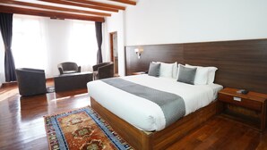 Une chambre spacieuse avec un grand lit, une tête de lit en bois et une table de chevet avec une lampe.