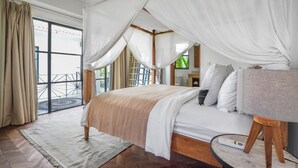 A spacious bedroom with a large bed, a bedside table, and a view of a balcony. - Mare Villa by Betterplace (Canggu)
