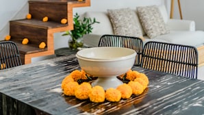 A modern kitchen with a marble countertop, a bowl of marigolds, and hanging light fixtures. - Mare Villa by Betterplace (Canggu)