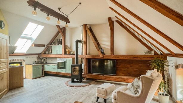 A cozy attic living space with a kitchen, a fireplace, a television, and a comfortable seating area. - Gemütliche Ferienwohnung am Kirschbaum in Malschwitz in der Oberlausitz (Malschwitz)