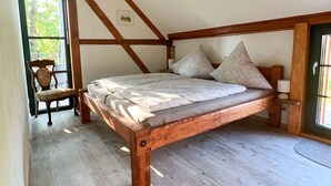 A wooden bed in a room with a sloped ceiling and a window. - Gemütliche Ferienwohnung am Kirschbaum in Malschwitz in der Oberlausitz (Malschwitz)
