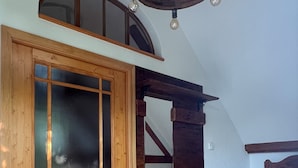 A wooden door with a glass panel, a staircase with wooden railings, and a round woven rug on a tiled floor. - Gemütliche Ferienwohnung am Kirschbaum in Malschwitz in der Oberlausitz (Malschwitz)