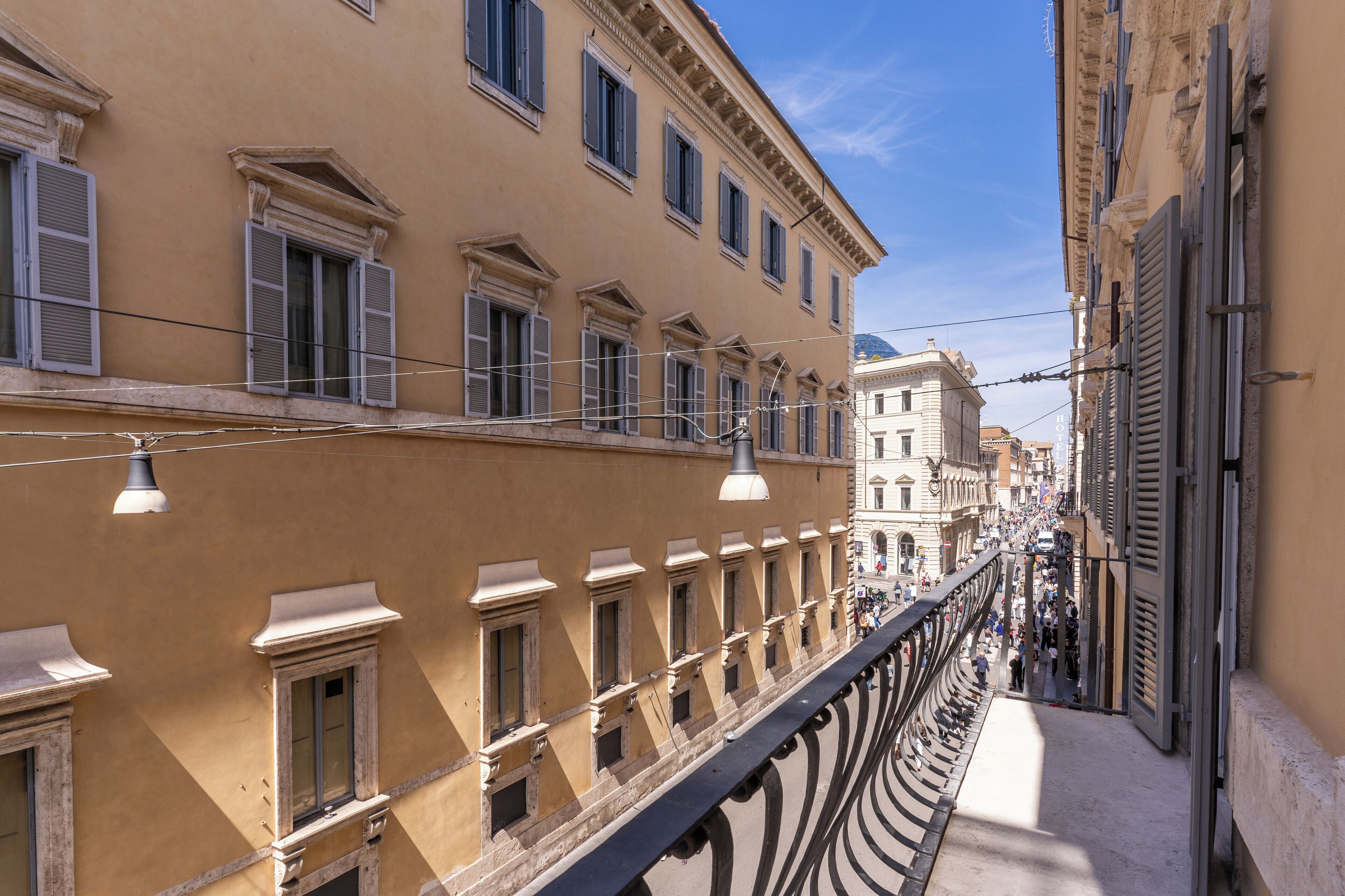 Une rue étroite bordée d’immeubles à l’architecture classique, avec notamment des fenêtres en arc et des moulures décoratives.