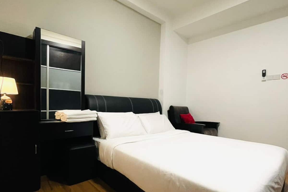 A hotel room with a bed, a nightstand, a dresser, and a wall-mounted phone.