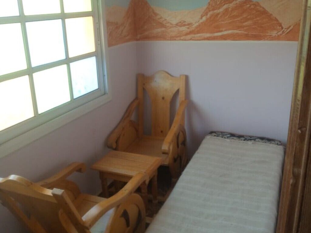 A room with a bed, a wooden chair, and a window.