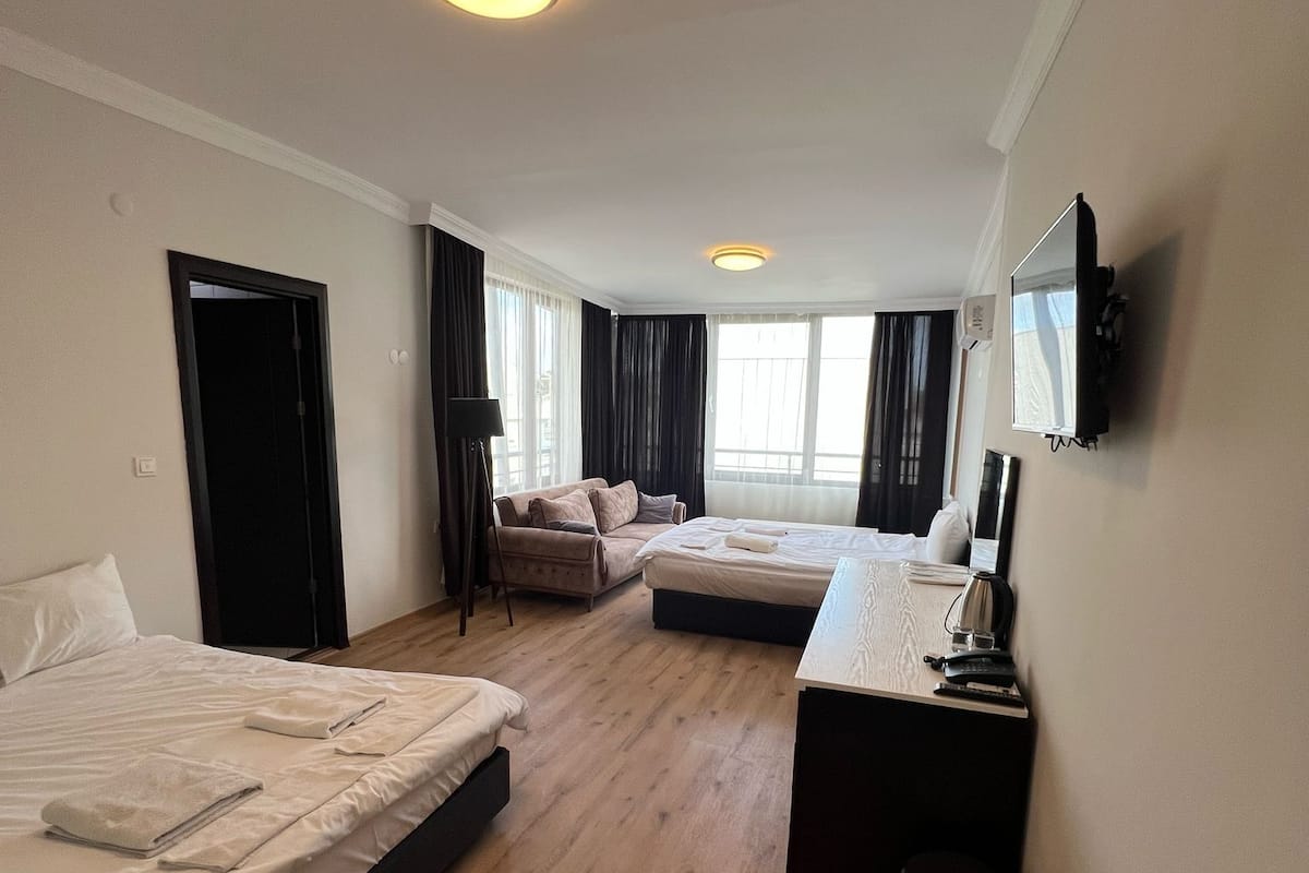Une chambre d’hôtel avec deux lits, un bureau, une télévision et une fenêtre avec des rideaux.