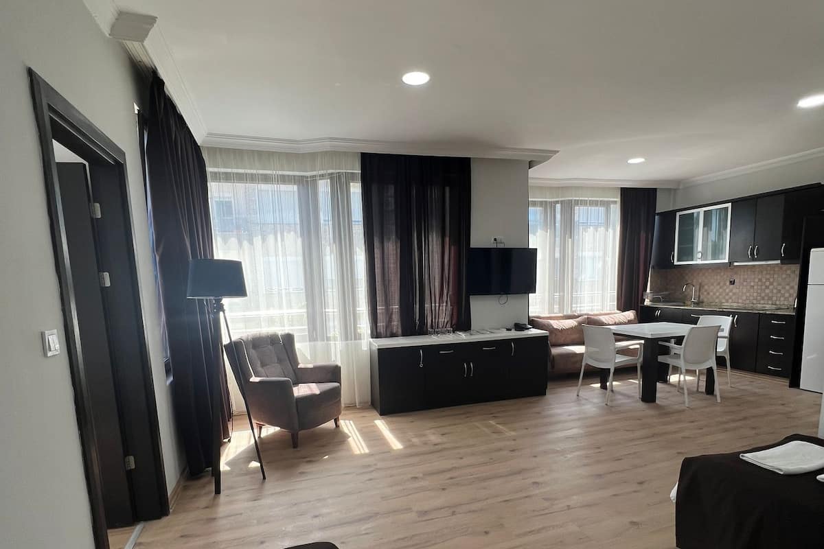 Une chambre d’hôtel moderne équipée d’un grand lit, d’un bureau, d’une chaise, d’un canapé et d’un coin cuisine.