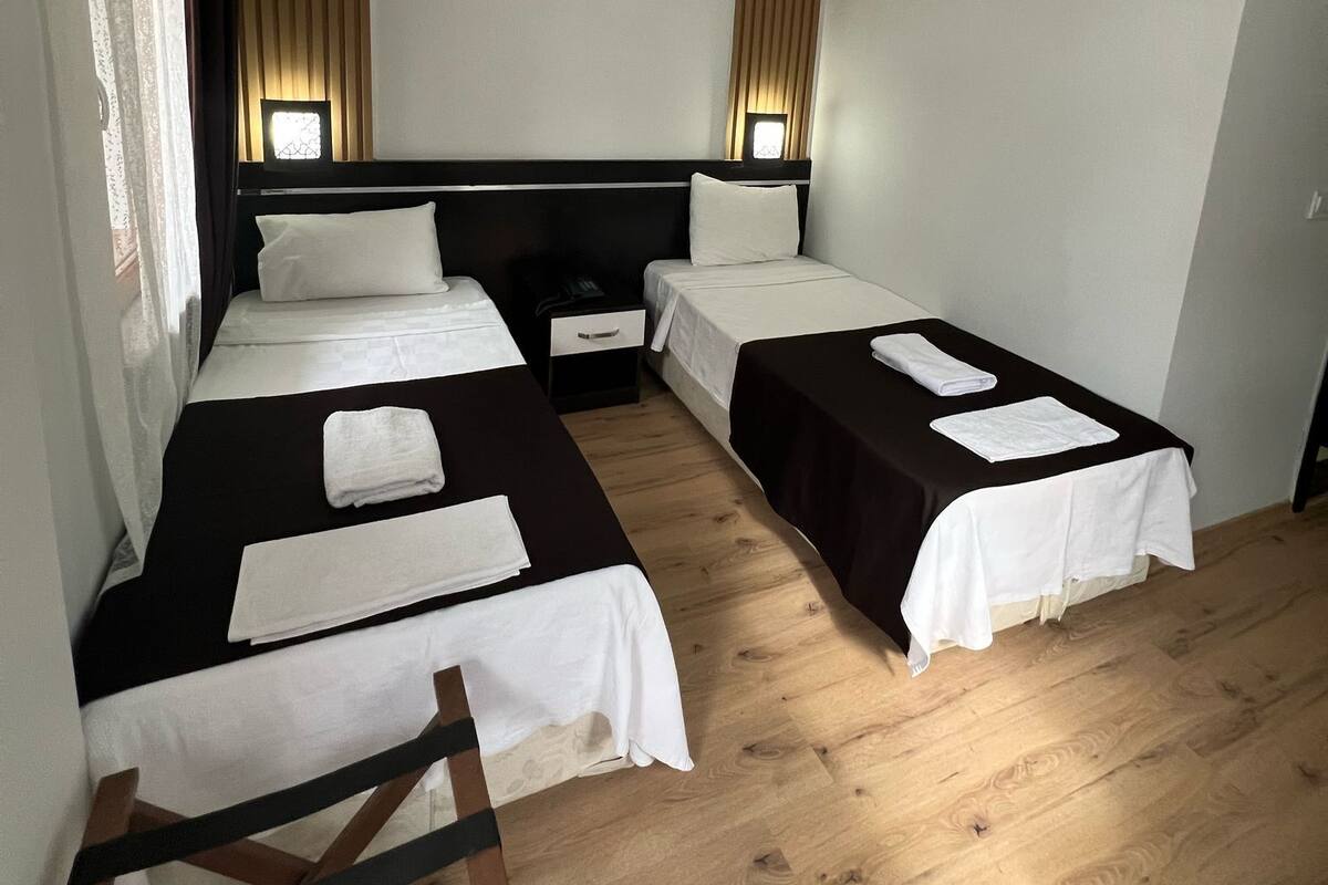 Une chambre d’hôtel avec deux lits, un plancher en bois et un climatiseur fixé au mur.