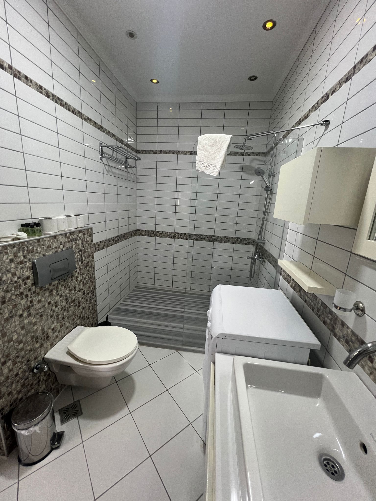 Un baño con inodoro, lavamanos, ducha y paredes de azulejos.