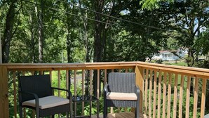 A wooden deck with two chairs and a railing.
