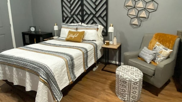 A bedroom with a bed, bedside tables, a chair, and a decorative wall piece.