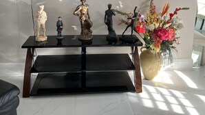 Una sala de estar con un centro de entretenimiento negro, un televisor de pantalla plana montado en la pared y un jarrón de flores sobre una mesa.