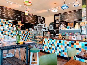 A café with a colorful tiled wall, a menu board, and a counter with various items.