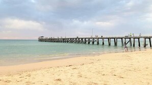 A beach with a pier extending into the water. - Your family & staff will love it here! Bed & bath linen hire included. Unlimited WIFI. Free, easy parking. Free child friendly amenities. Keyless access. Easy self check in. No stairs! (Richmond)