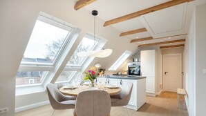Eine moderne Küche mit Essbereich, großen Fenstern und einer Loft-Decke.