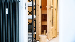 A wooden sauna room with a bench, towels, and a bucket.