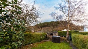 A well-maintained garden with a small shed, neatly trimmed hedges, and a grassy area. - Oak House (Machynlleth)