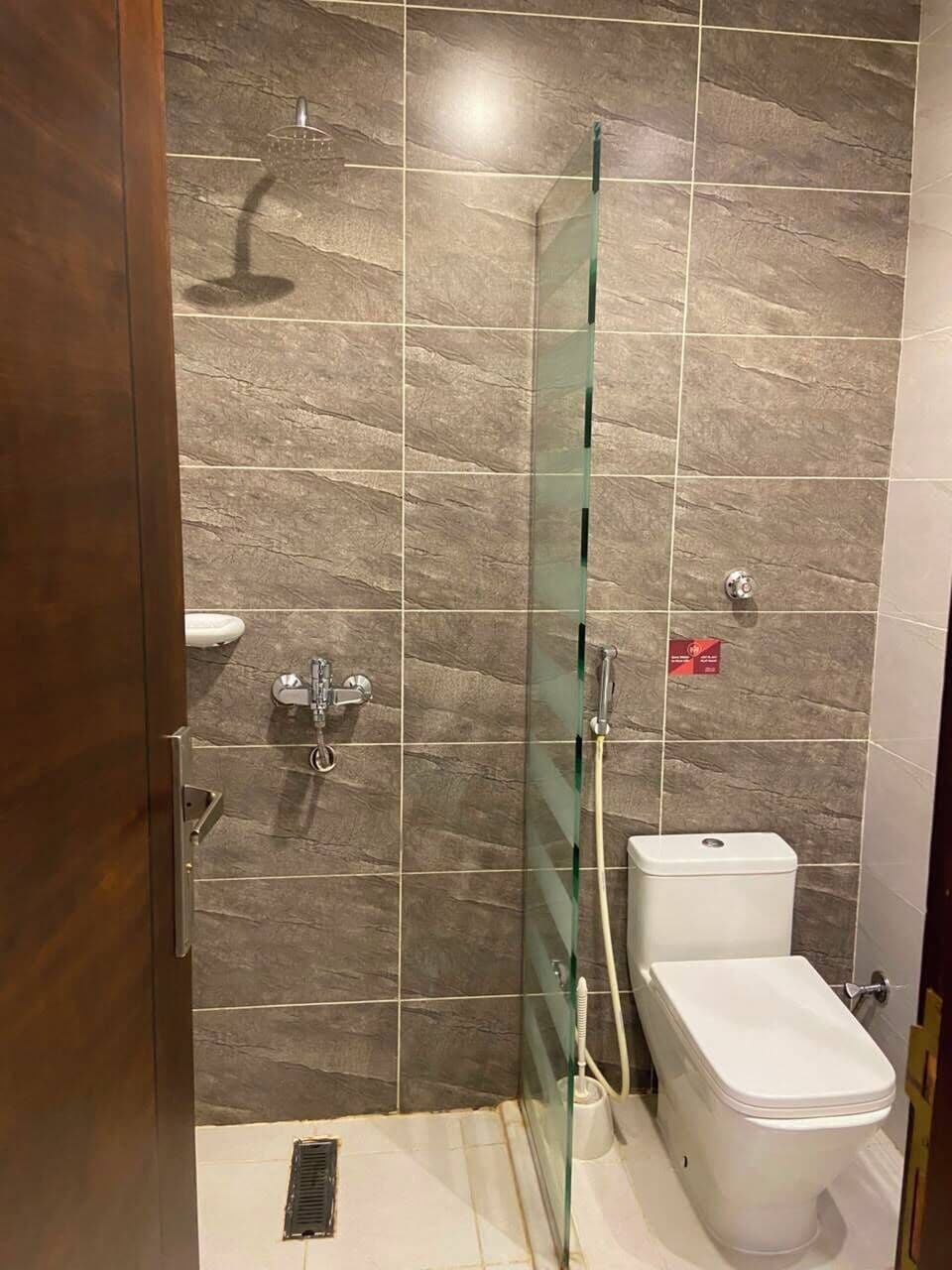 A bathroom with a glass-enclosed shower, a toilet, and a sink.