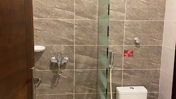 A bathroom with a glass-enclosed shower, a toilet, and a sink.