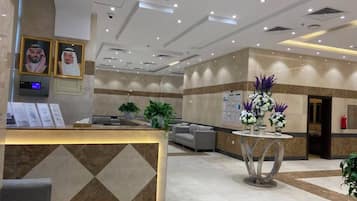 Un hall de hotel con mostrador de recepción, zona de estar y plantas decorativas.