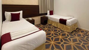 Een hotelkamer met twee bedden, een nachtkastje en een kamerbreed tapijt met een patroon.