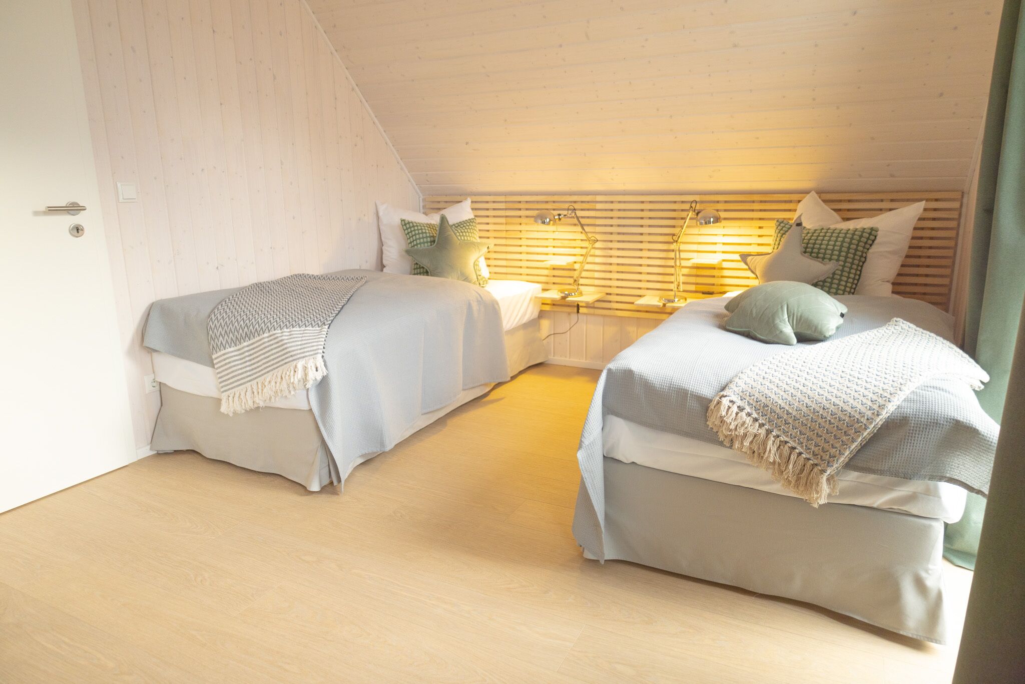 Un dormitorio con dos camas, cabeceras de listones de madera y lámparas de noche.