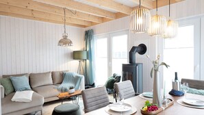 Ein gemütliches Wohnzimmer mit einer Couch, einem Esstisch, Stühlen, einem Kamin und hängenden Pendelleuchten.
