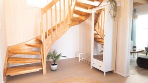 Eine Holztreppe führt zu einem Erkerbereich mit einem weißen Schrank und einer hängenden Pflanze.
