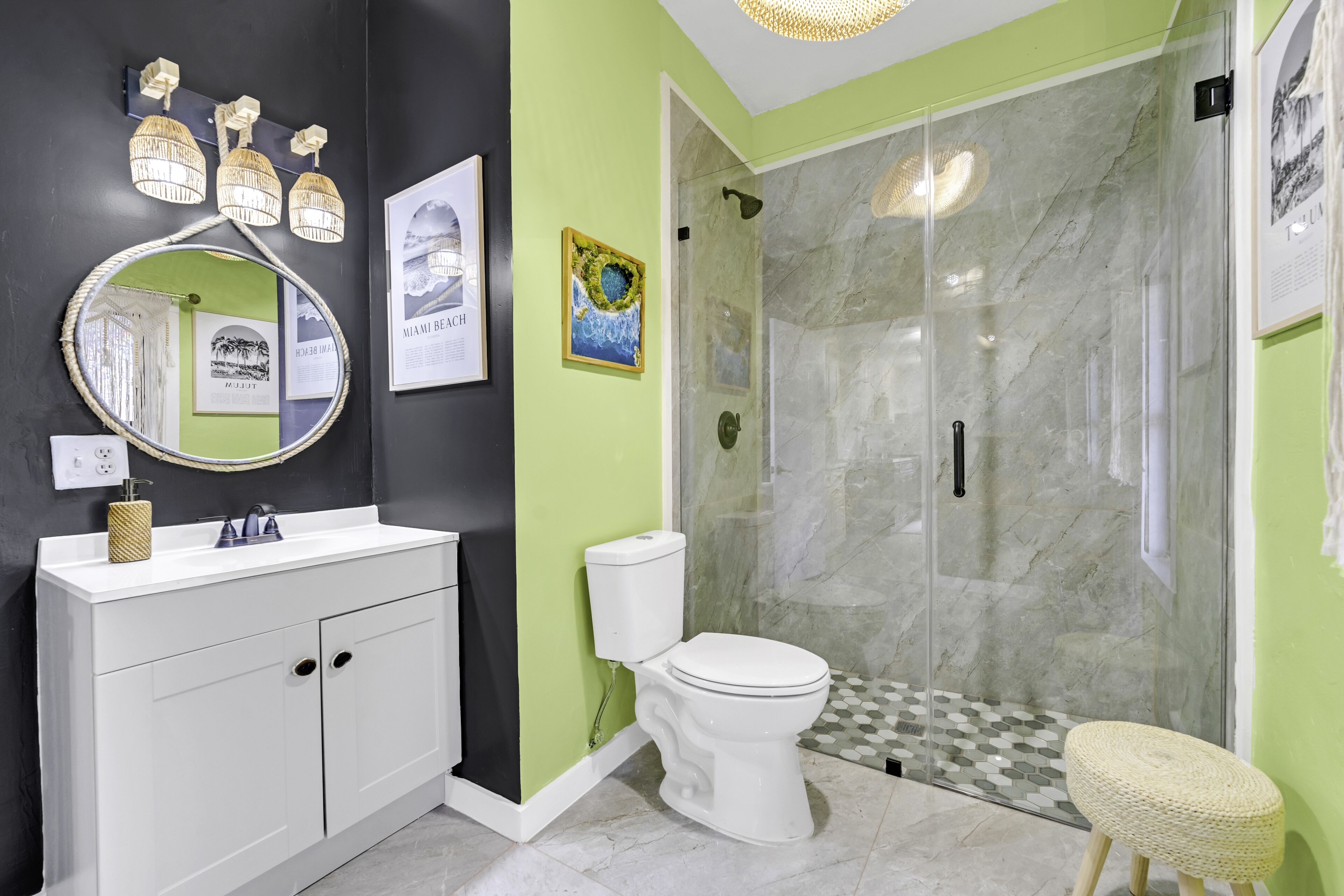 Un baño moderno con tocador blanco, espejo redondo y cabina de ducha con mampara de vidrio.