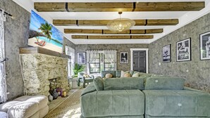A cozy living room with a green sofa, a stone fireplace, and a beach-themed painting on the wall. - Casa Alaïa | West Brickell | Sleeps 20 | Pool&Spa (Miami)