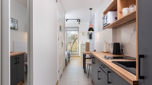 A modern kitchen with a wooden countertop, a built-in sink, and a pendant light. - APARTAMENTY NA DĘBNIKACH (Kraków)
