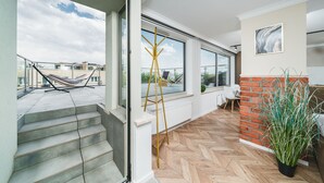 A modern interior with a herringbone floor, large windows, a brick accent wall, and a potted plant. - APARTAMENTY NA DĘBNIKACH (Kraków)