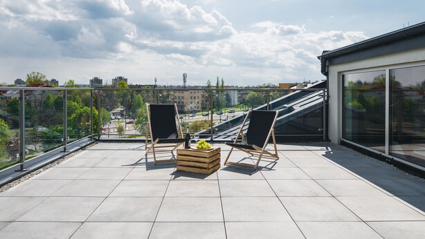 A rooftop terrace with two lounge chairs, a wooden crate with a bottle and grapes, and a city view. - APARTAMENTY NA DĘBNIKACH (Kraków)