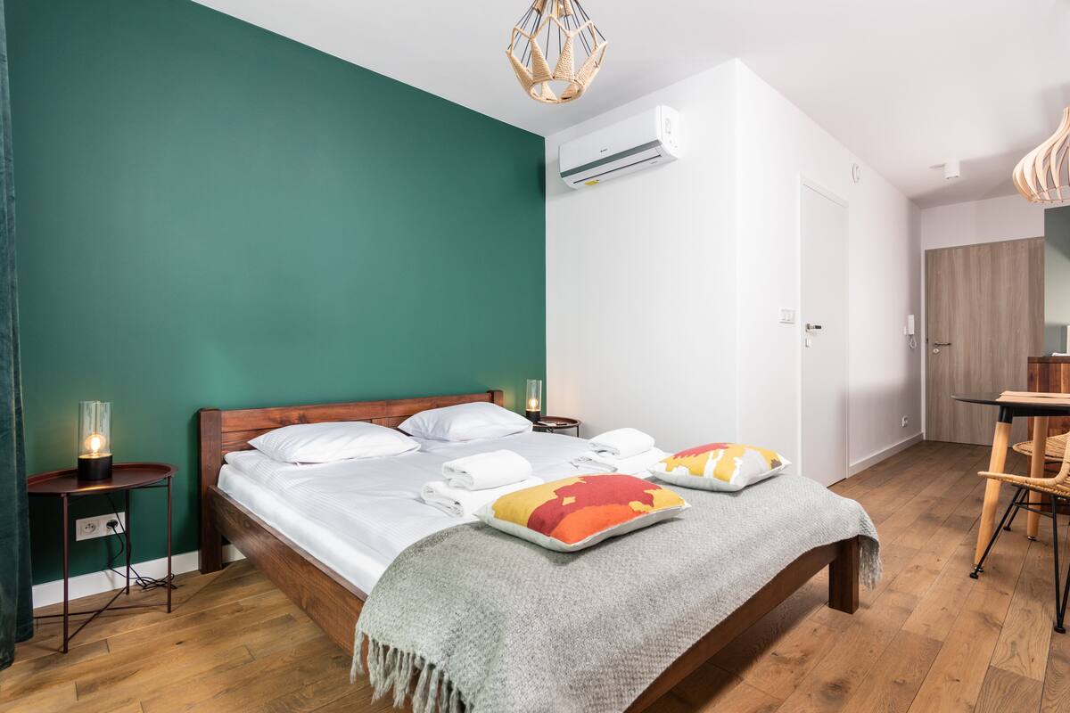 A bedroom with a bed, bedside table, and an air conditioning unit.