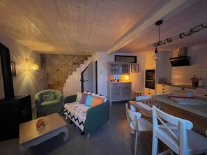 Una sala acogedora con sofá, una mesa de comedor y una cocina con escalera.