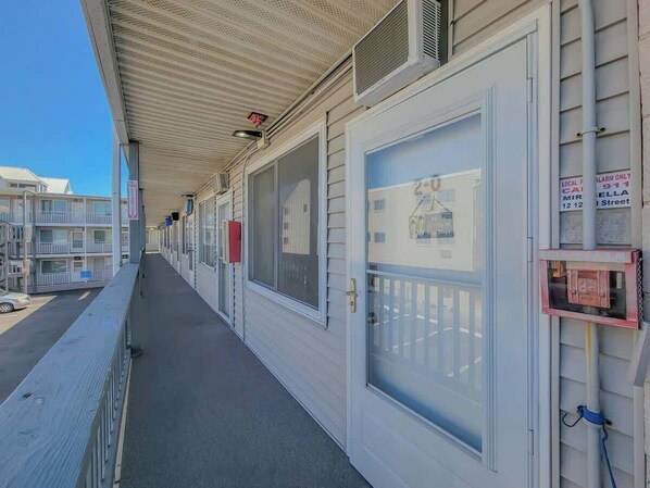 A motel with a covered walkway, large windows, and a sign indicating a local fire alarm.