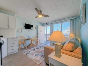 A compact living space with a kitchenette, a dining area, a sofa, and a ceiling fan.
