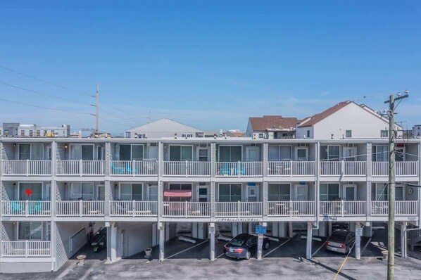 Un motel de varios pisos con un patio central, garaje de estacionamiento y un cielo azul despejado.