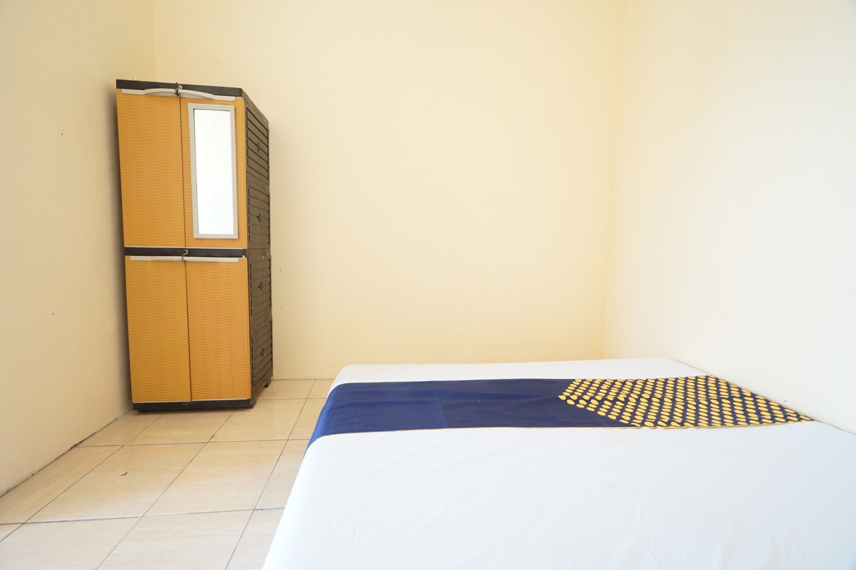 A small, single-room hotel room with a bed, a wardrobe, and a window.
